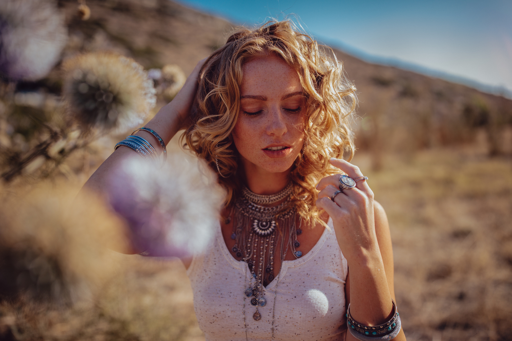 Beautiful bohemian girl day dreaming in field at sunset